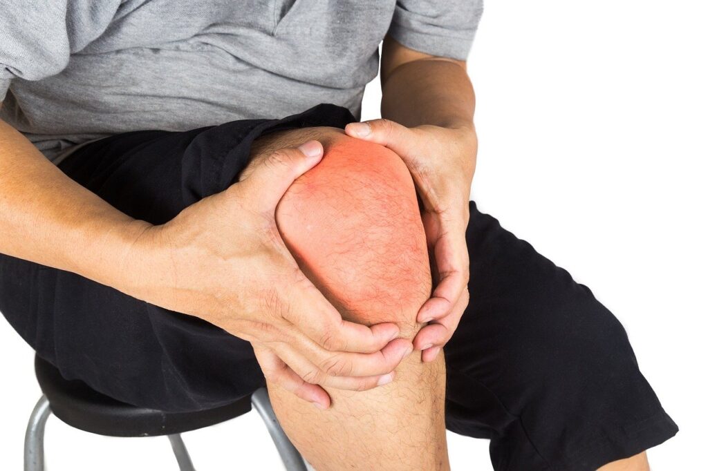 Übungen gegen Knieschmerzen: Mann mit Händen am gebeugten Knie